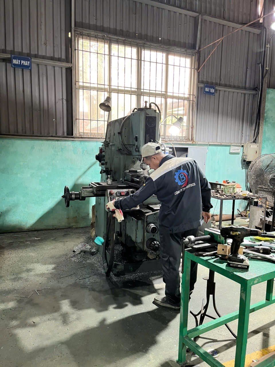 A worker operating a milling machine in a machining workshop.