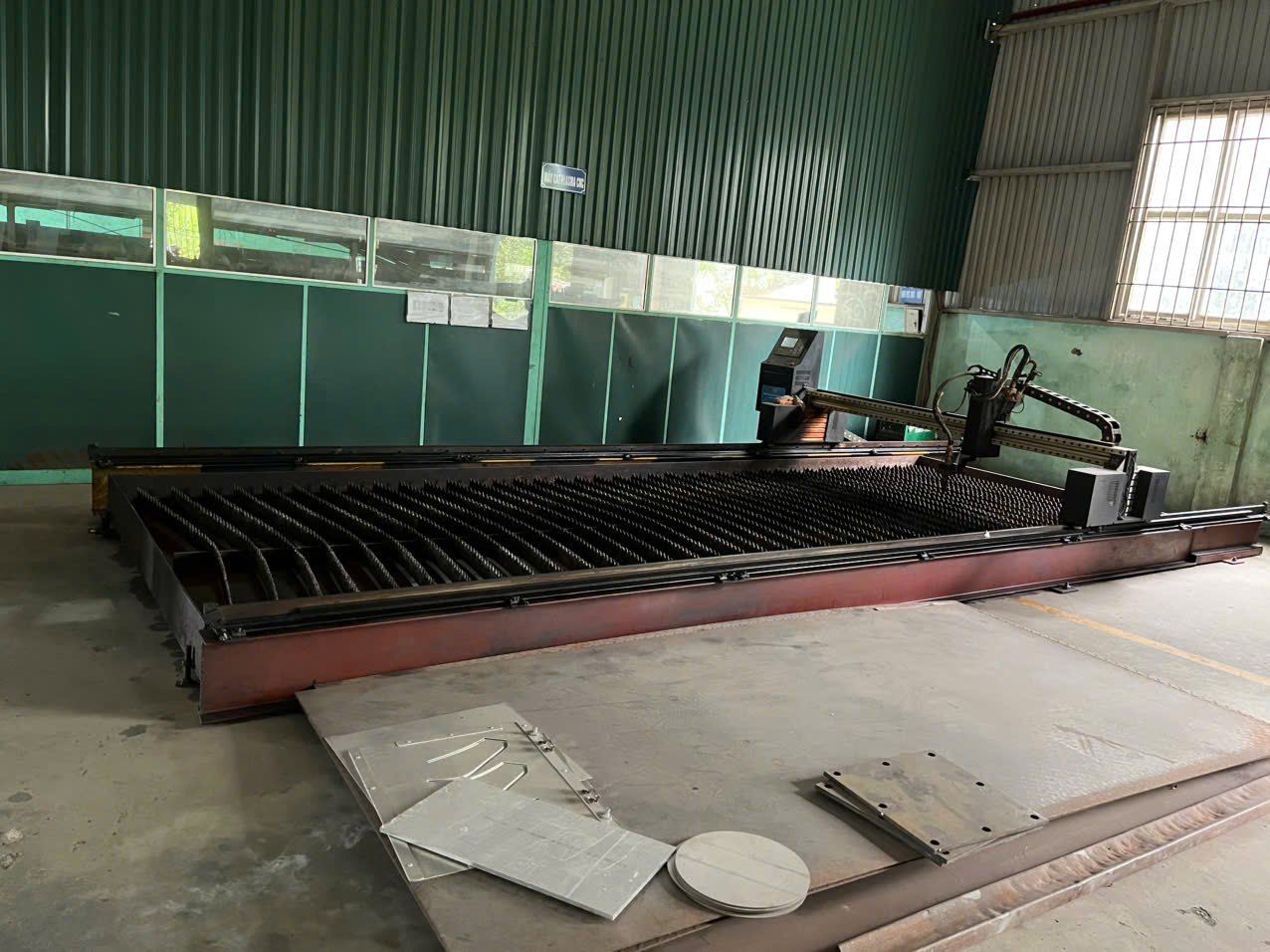 A large CNC cutting table in a factory hall.
