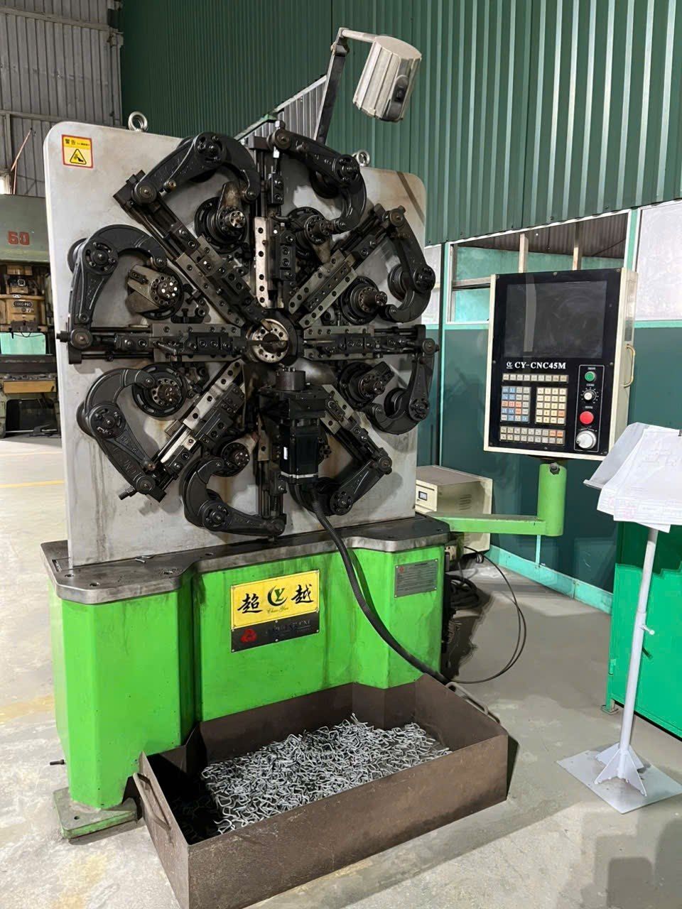 A CNC spring-forming machine with a control panel.
