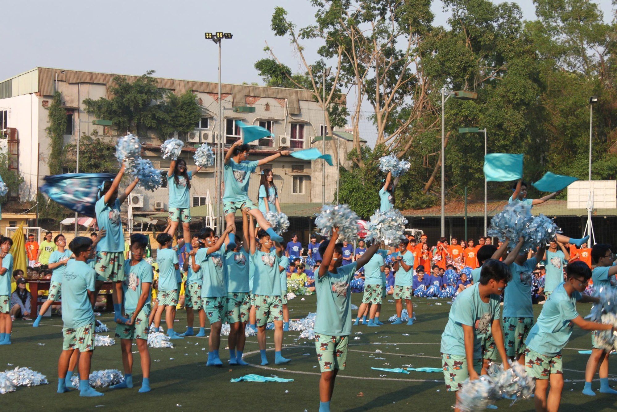 Cheerdance team performing a lift with pom-poms on the school field.