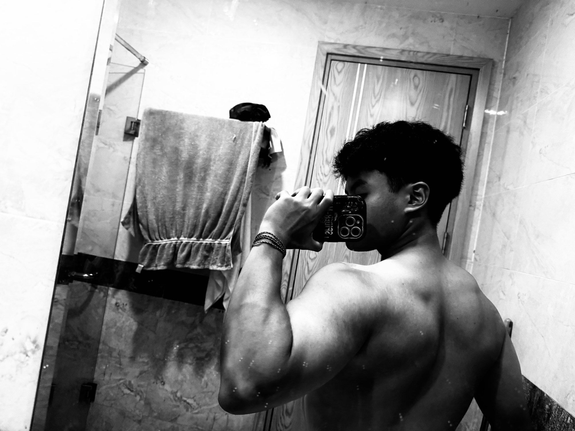 Black-and-white mirror photo of Bao from behind, flexing after a workout.