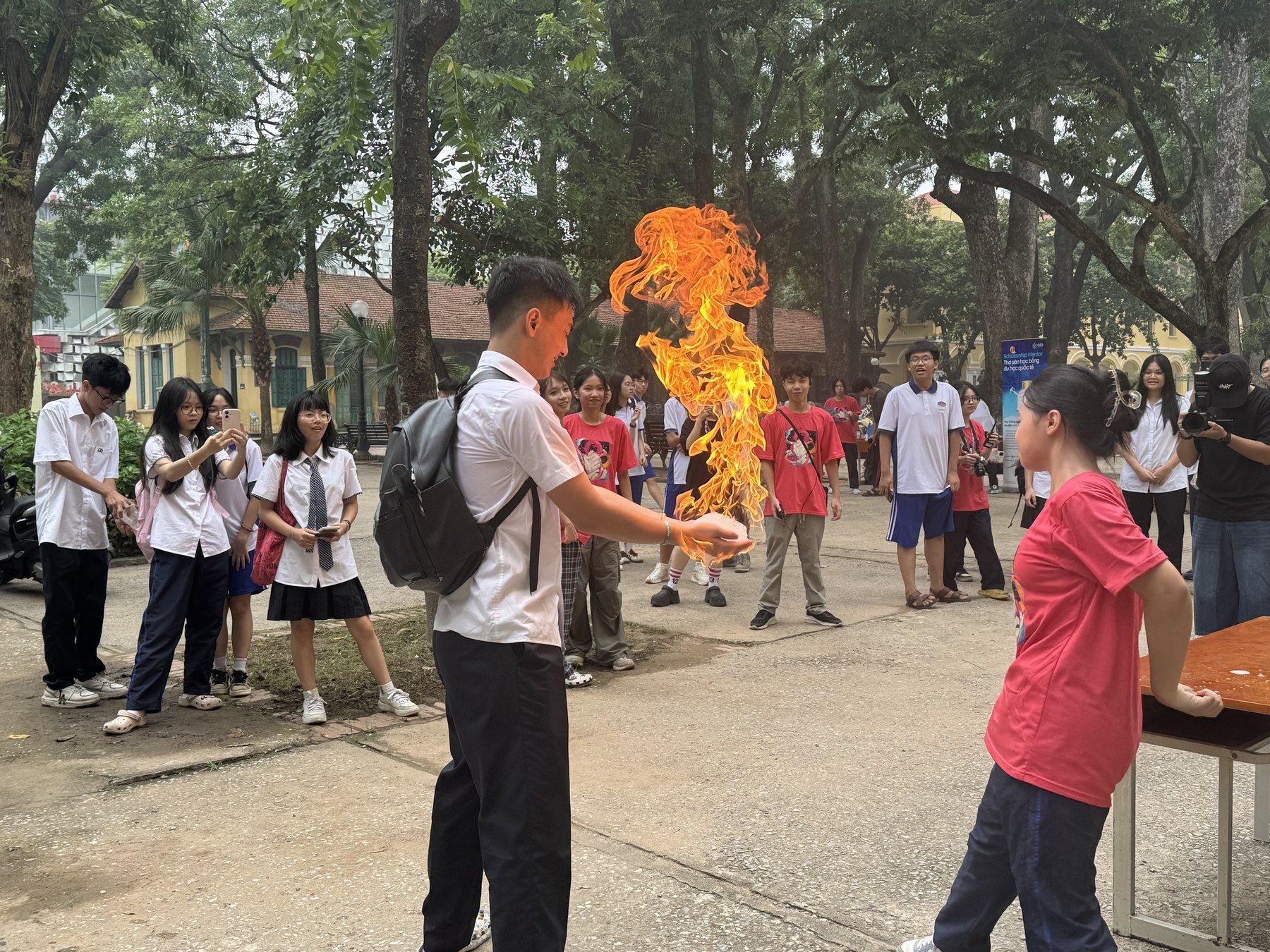 Students watching an outdoor science demonstration with a flame.