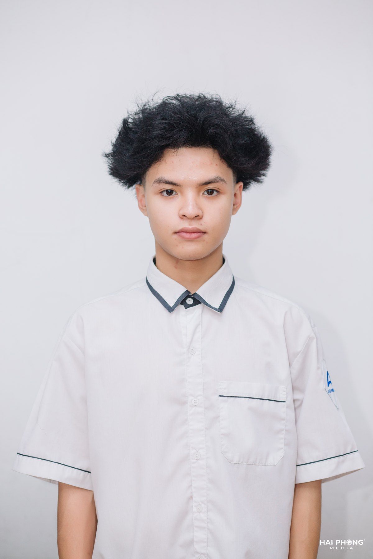 Studio portrait of Bao in a white school shirt.